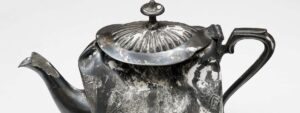 The lid of a very battered metal tea pot