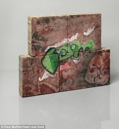 Graffiti type artwork with a green alien like character painted across four bricks.