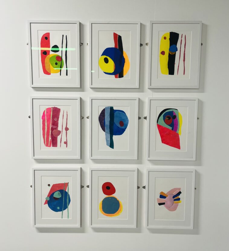 A series of 9 framed abstract prints hung together on a white gallery wall.