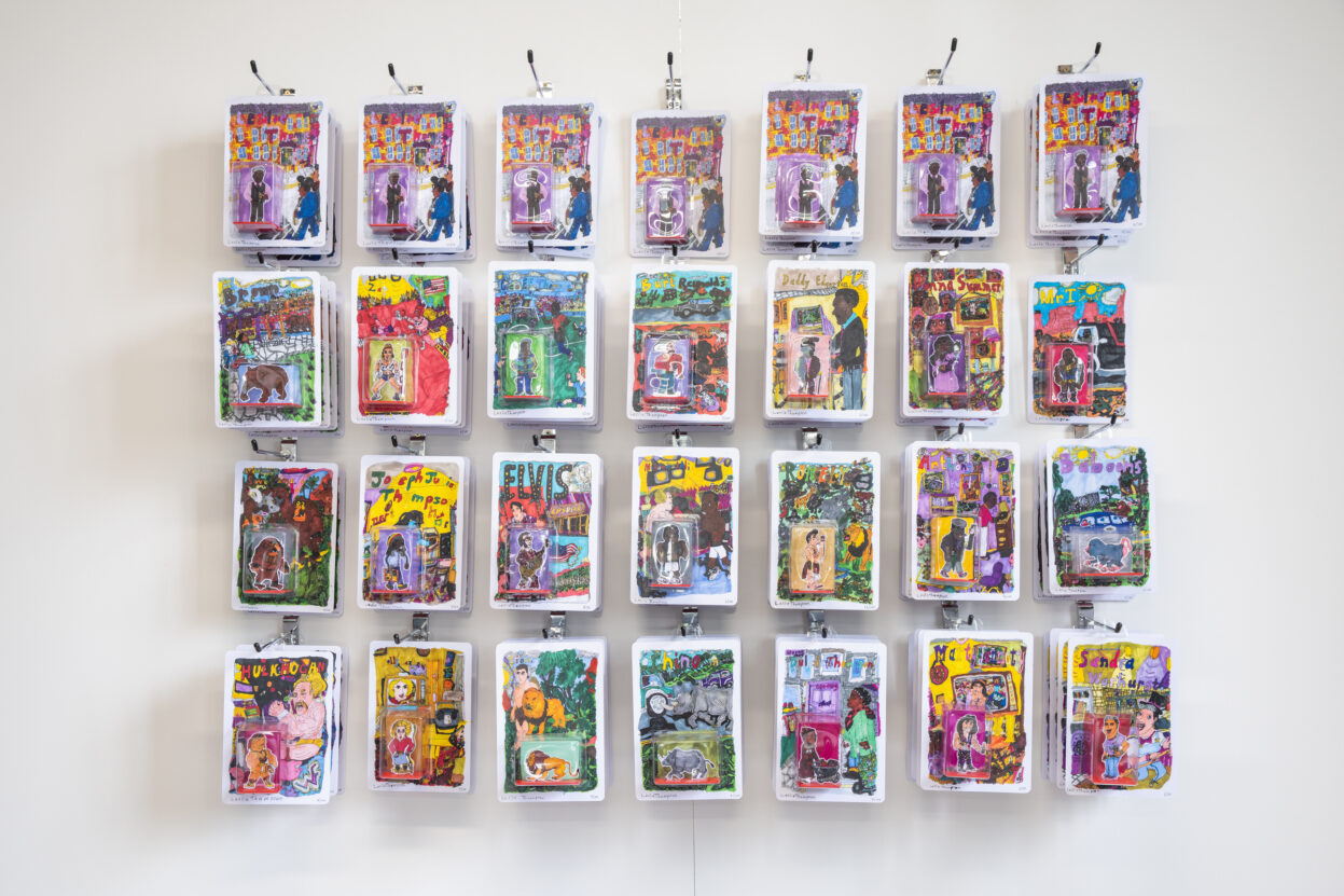 An installation of packaged hero figurines hung on a white gallery wall.
