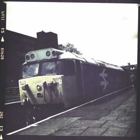 Aged or old photograph of a train waiting at a station platform.