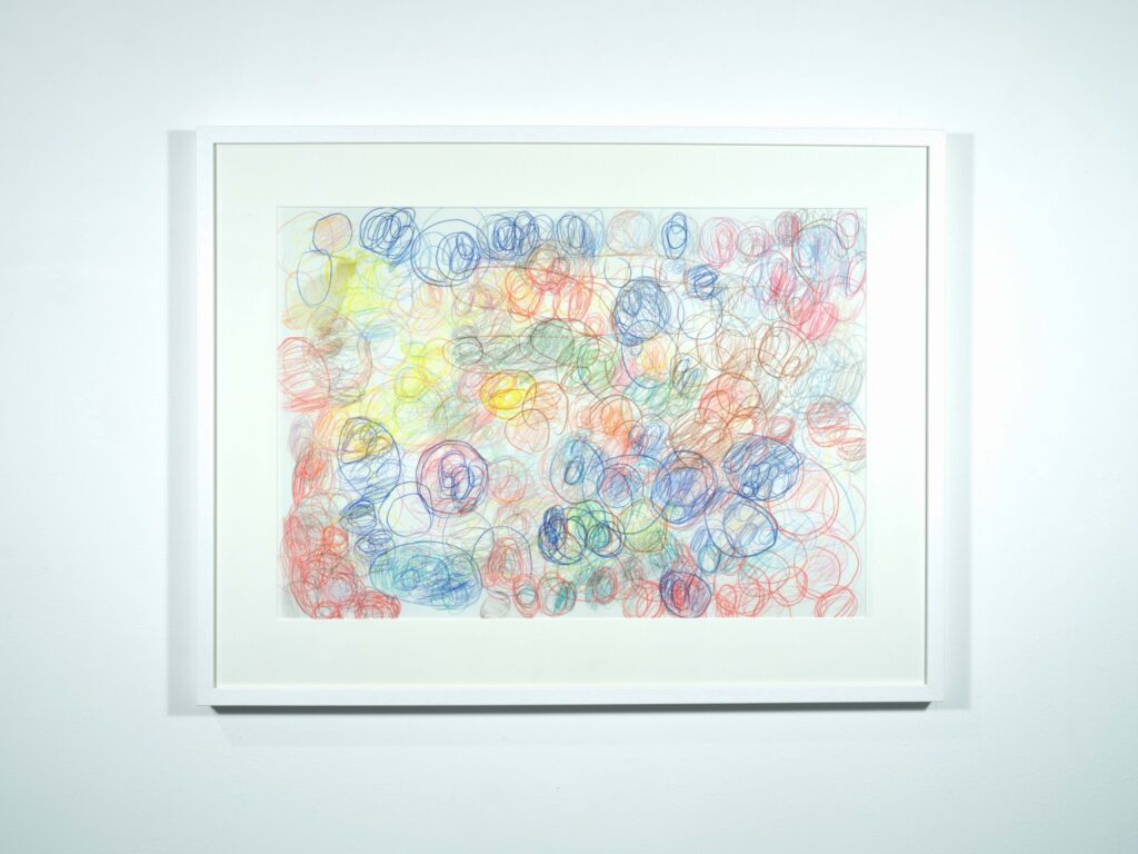 Framed abstract artwork of colourful swirls, hung on a white gallery wall.