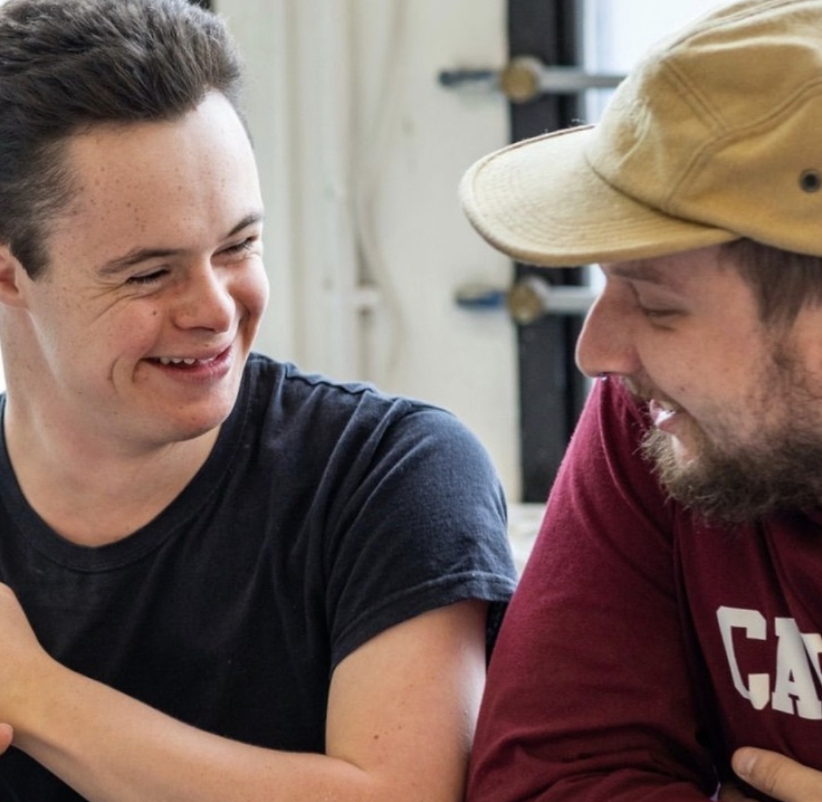 A young artist and volunteer sitting together and smiling