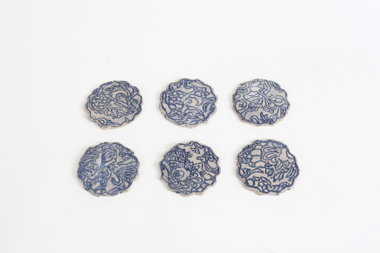 Six round ceramic tiles with a blue and white floral pattern, by Sarah Lee