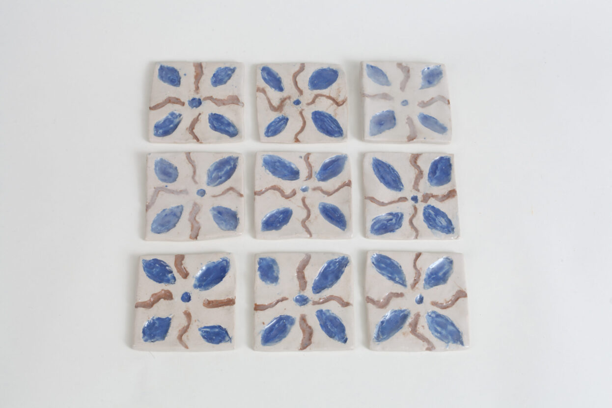 Nine square ceramic tiles with a floral pattern in blue, by Sarah Lee