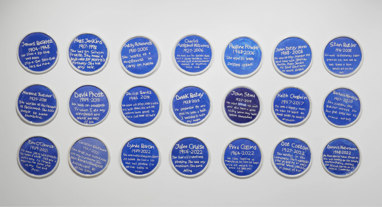 21 blue plaques on white wall each with white writing on