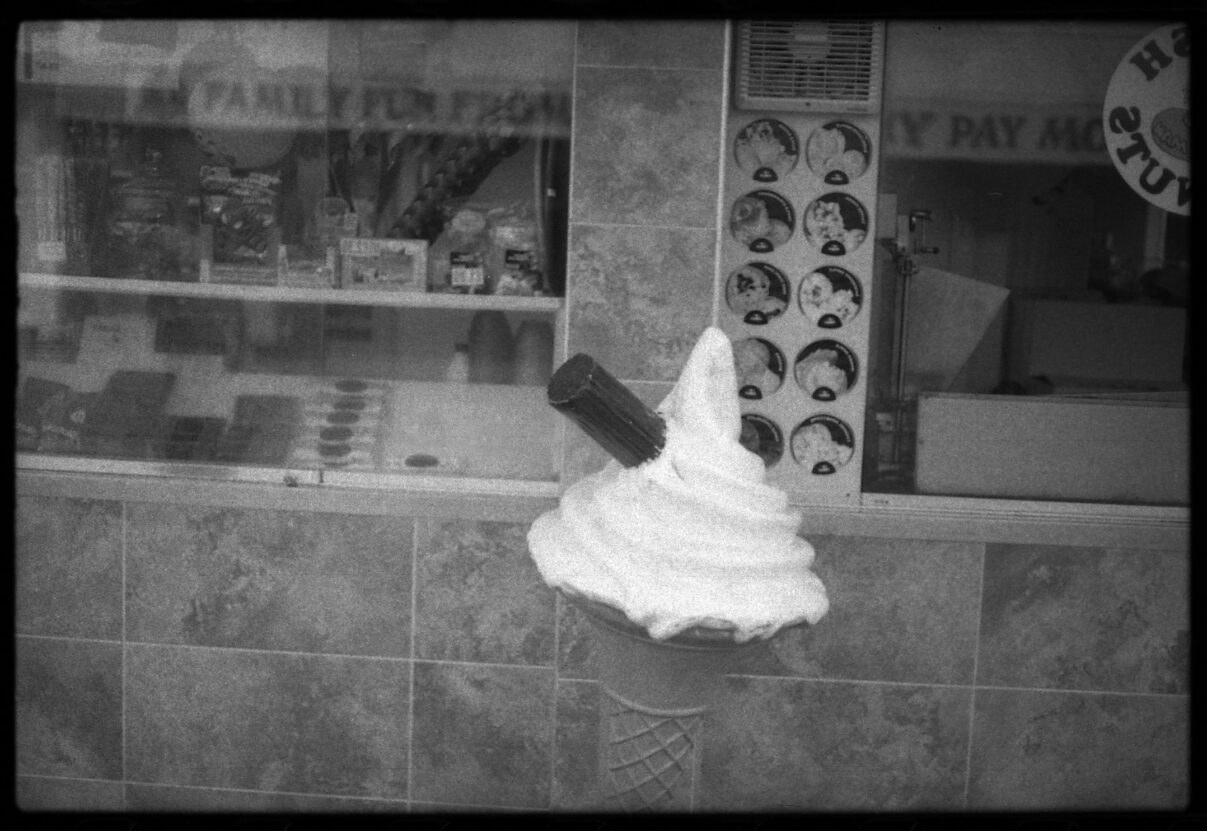 black and white photo of an ice cream in front of a shop
