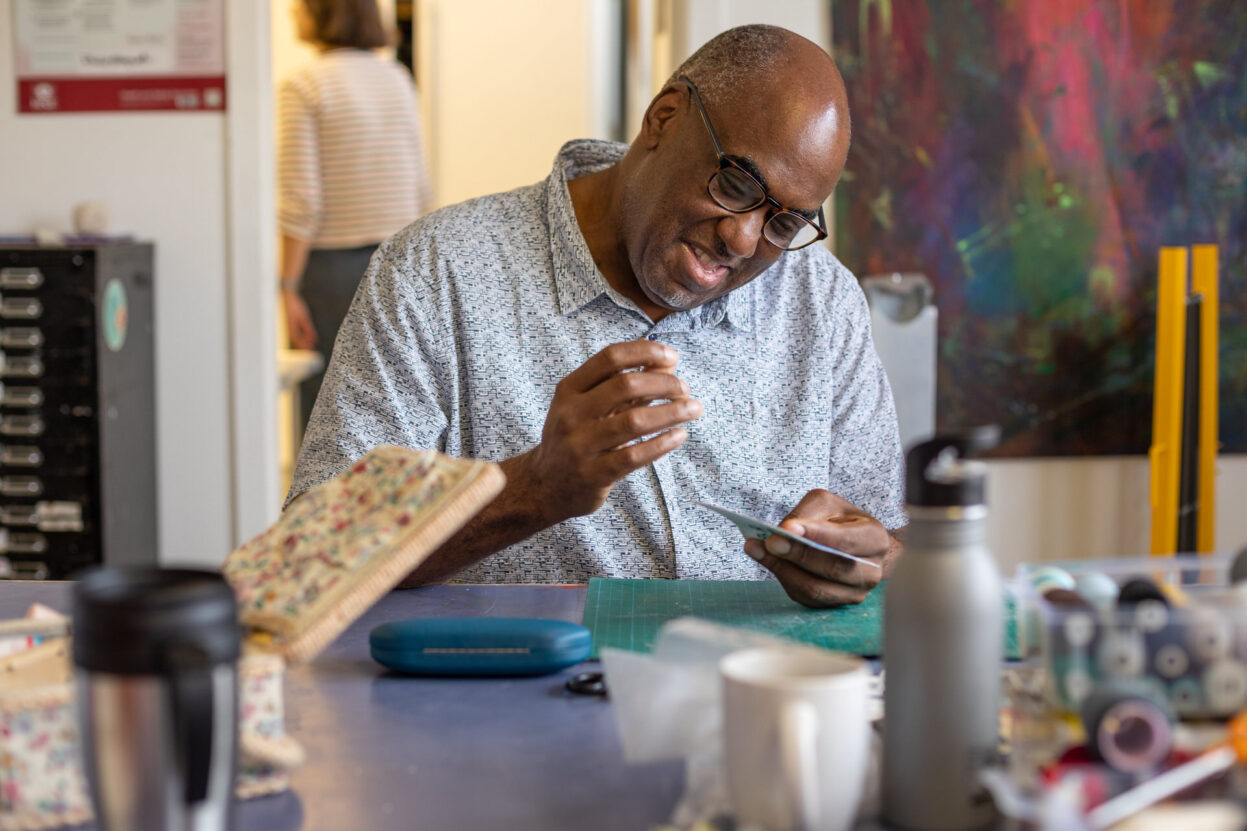 Artist Horace Lindezey at Venture Art's studio, smiling whilst working on an embroidery project