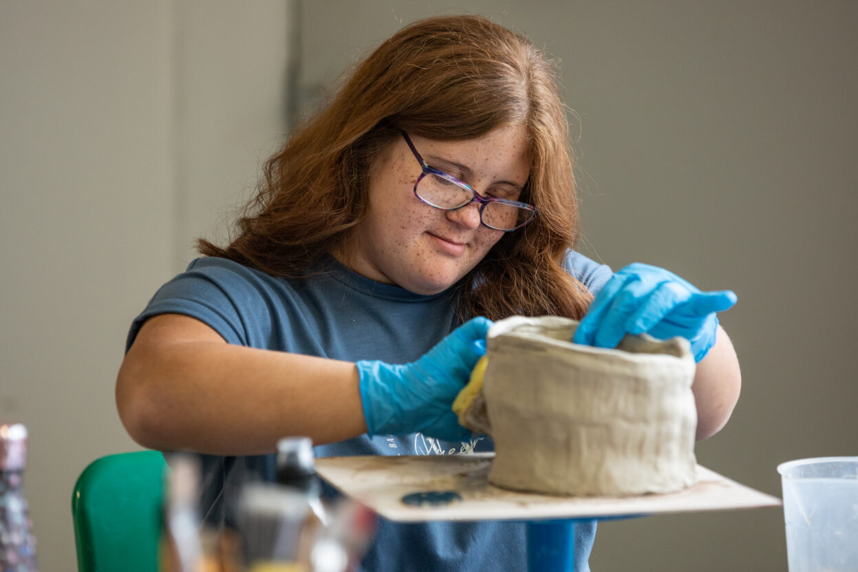 A young female artist working on a ceramic pot