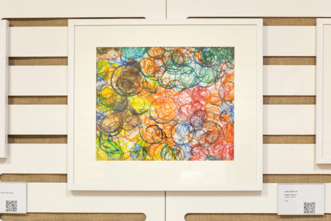 Multi-coloured abstract artwork, framed and on display on a wall.