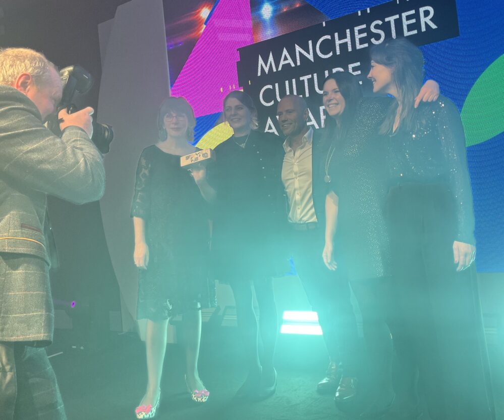 A group of people holding an award being photographed.