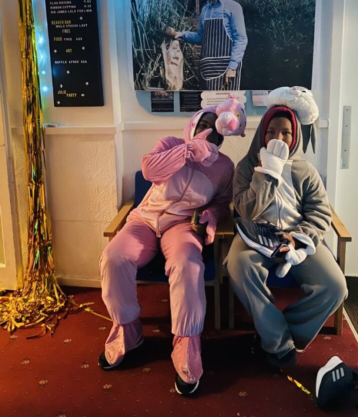 Two people sat down in fancy dress rabbit costumes, one pink and one grey, at VA Collective event, The Julie Party.