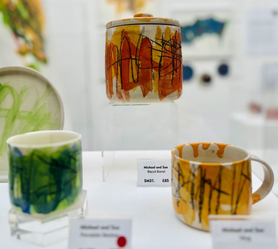 Three ceramic pots in a glass case.