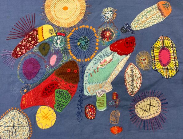 Textile Art made with appliqué and embroidery. Background blue. Lots of details made with different stitches.