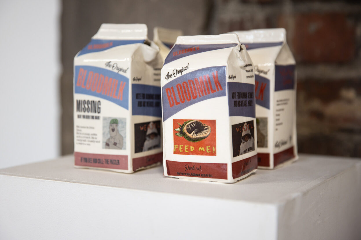 Ceramic milk cartons with the words Blood Milk painted on the side.