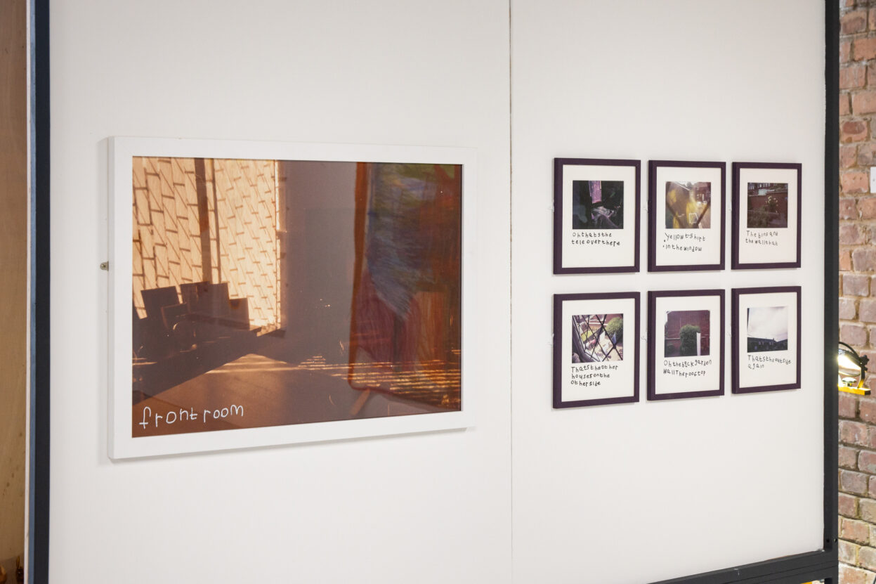 Framed photographs of everyday life, hung in white frames on white gallery wall.