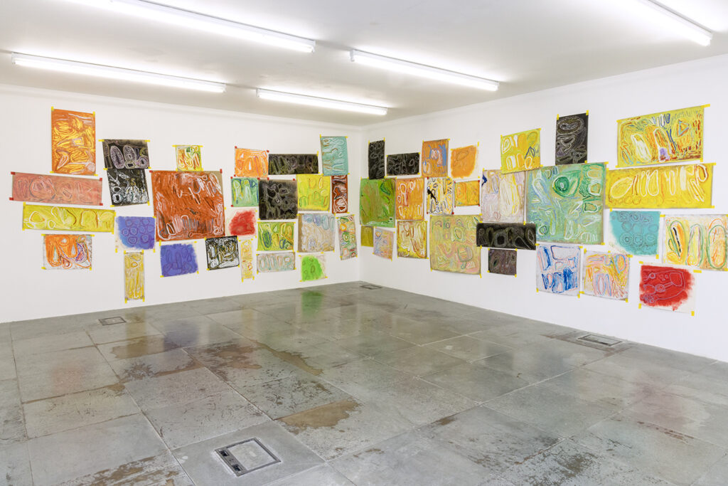 Two white gallery walls covered in colourful abstract artworks.