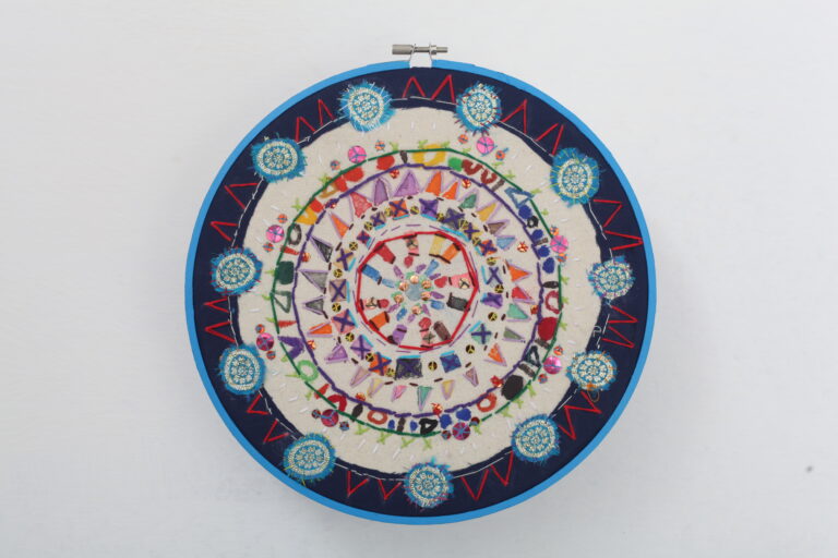 A textile mandala in a blue ring.