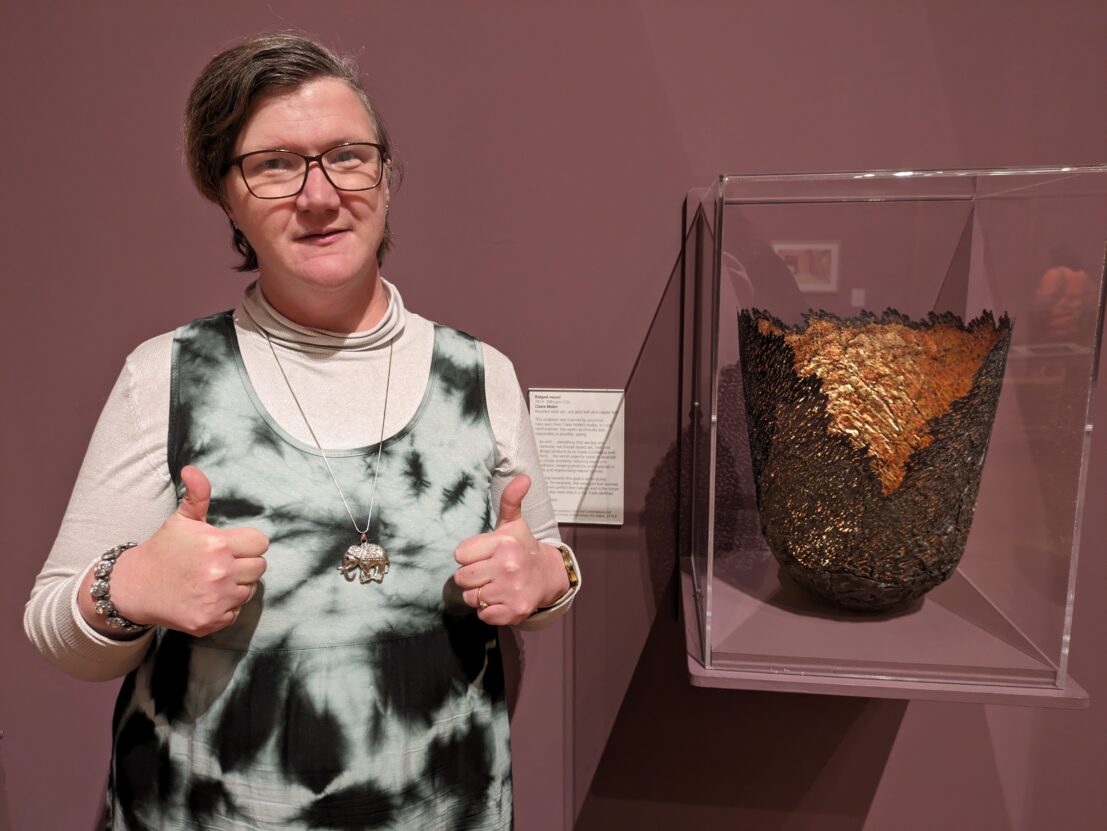Louise Hewitt stood in front of a vase in a glass case with her thumbs up.