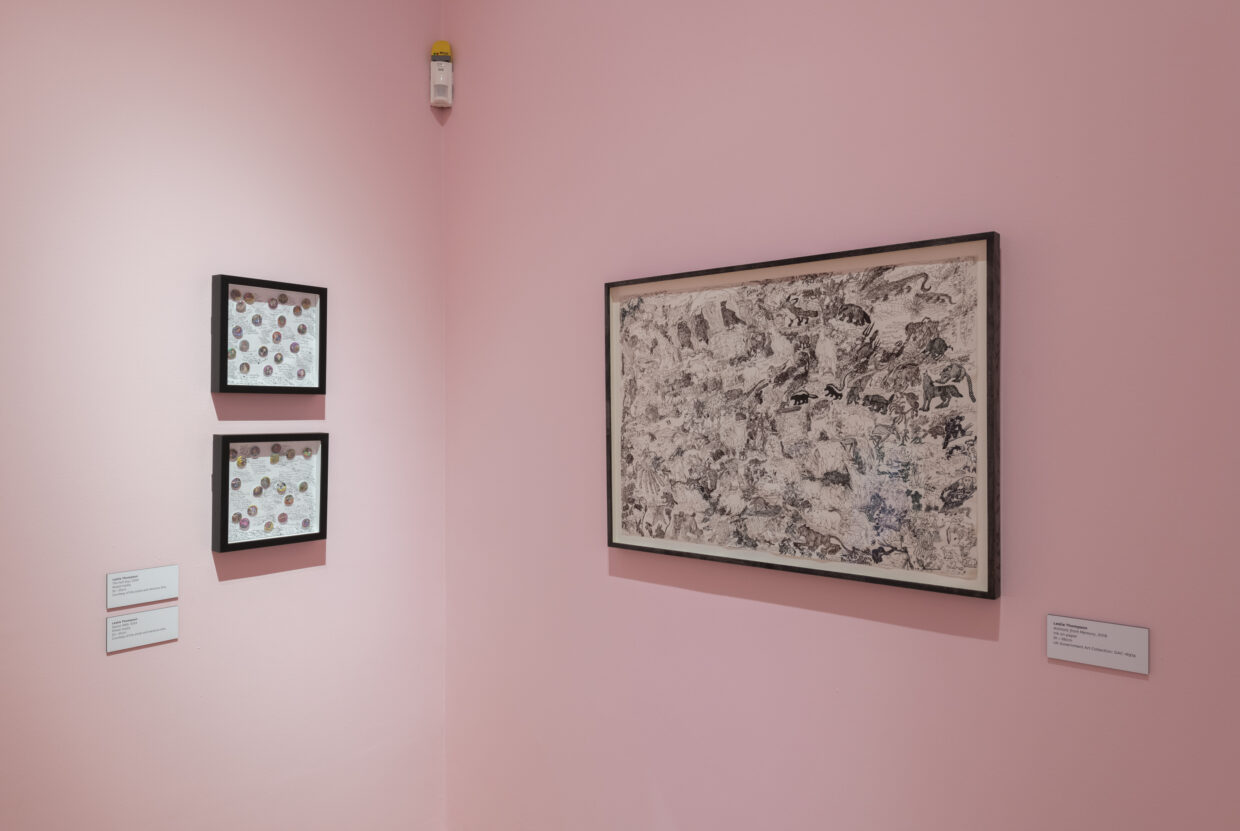 Three framed artworks hung on a pink gallery wall.