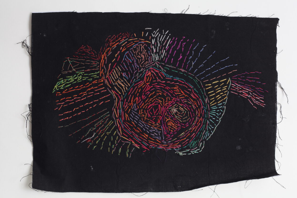 Firework design embroidered on to piece of black textile by Emma Horton.