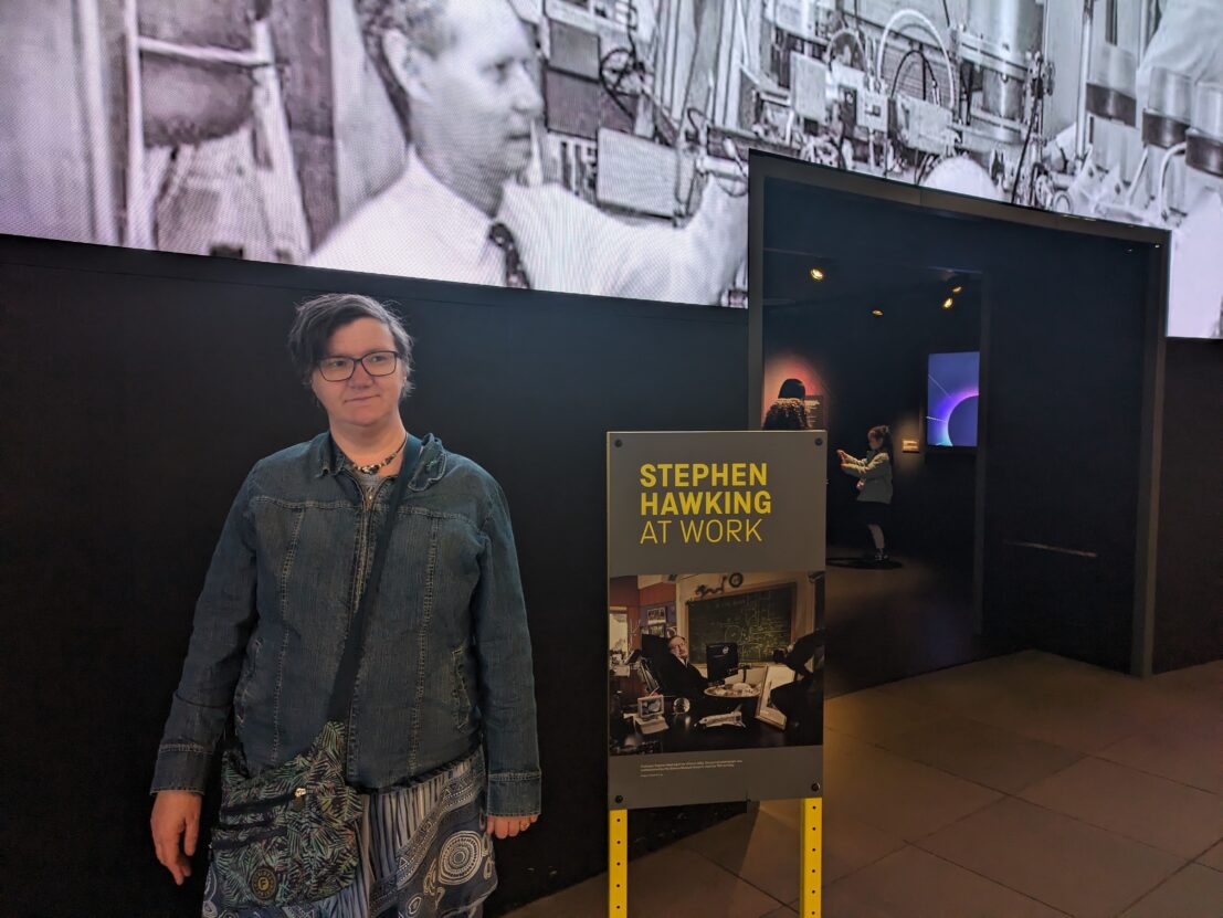 Louise Hewitt stood in front of a picture of Stephen Hawking.