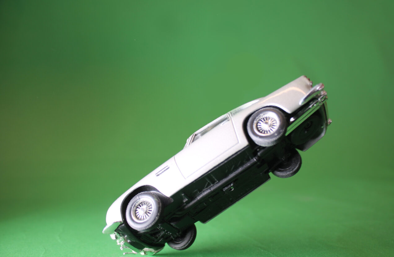 A photo of a toy car falling through the air against a green background.