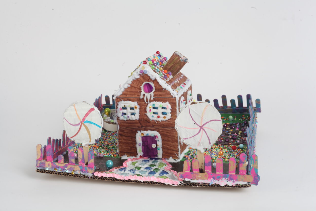 A mixed media model of a ginger bread house.