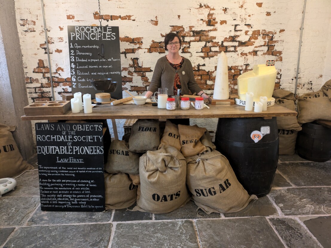 Louise Hewitt stood behind a mocked up shop front in the Rochdale Pioneers museum