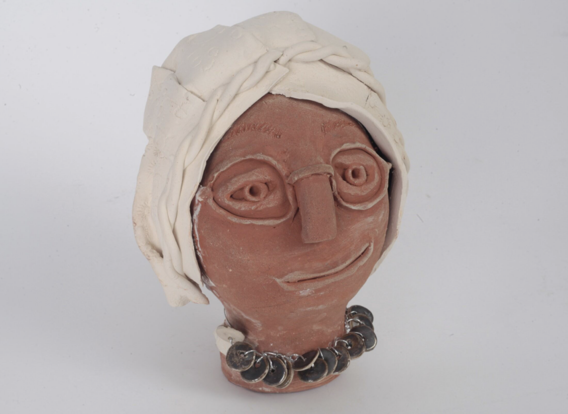 Deborah Makindie work My Mum From Ghana will be on display at Venture Arts Full Studio Show. The ceramic work is a sculpture of Deborah's mum's head and it shows a woman with brown skin wearing thin rimmed glasses with a white scarf covering her head.
