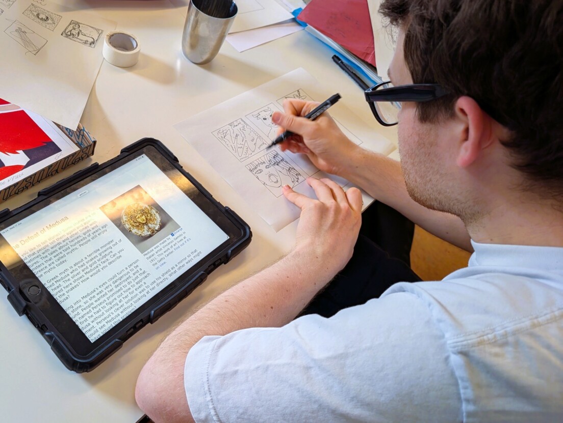 Venture Arts artist George Parker-Conway drawing at a table with an iPad in the studio.